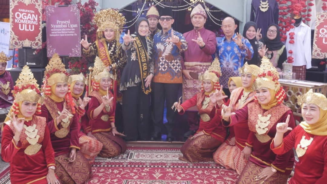 Bupati OKU H. Teddy Meilwansyah bersama Ketua TP PKK Hj. Zwesty Karenia Teddy dan Kepala Disarpus OKU Ahmad Azhar berfoto bersama penari dalam prosesi adat Nyambai Ugan di Stand Disarpus OKU pada Festival Literasi Sumsel 2025 di Asrama Haji Palembang, Jumat (7/11/2025). (Foto : ist)